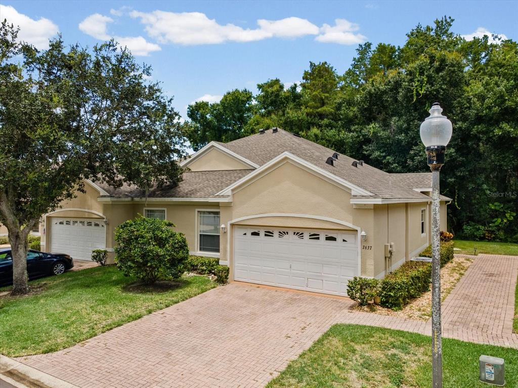 A beige single-story house with a two-car garage and a brick paver driveway — 7637 WIMPOLE DRIVE, NEW PORT RICHEY, FL