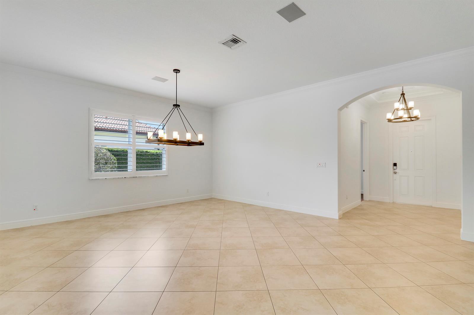 An empty dining room features tile flooring, white walls, and a modern chandelier — 119 Steeple Circle, Jupiter FL 33458, JUPITER, FL