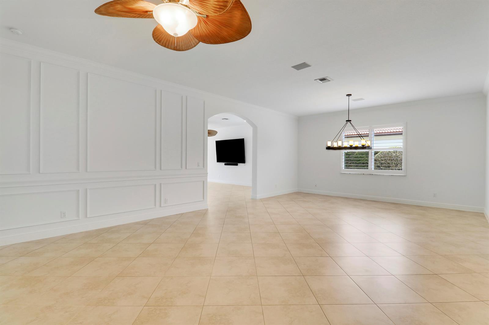 A spacious room features white wainscoting, tile flooring, a ceiling fan, and a chandelier — 119 Steeple Circle, Jupiter FL 33458, JUPITER, FL