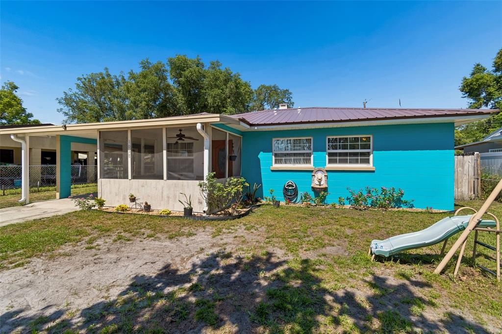 A bright blue house with a screened-in porch, metal roof, and a slide in the yard — 1038 CANAL DRIVE W, LAKELAND, FL