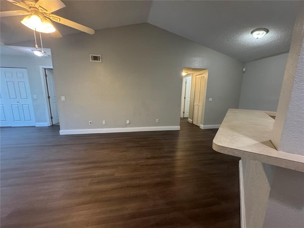 An interior view of a living area featuring vaulted ceilings, wood-look flooring, and a breakfast bar — 4532 COMMANDER DRIVE UNIT 2131, ORLANDO, FL
