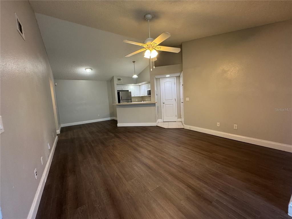 A living room with wood-look flooring, a ceiling fan, and an open kitchen area — 4532 COMMANDER DRIVE UNIT 2131, ORLANDO, FL
