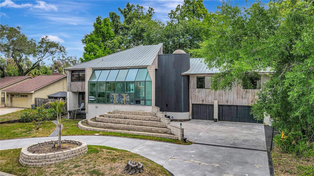 A modern house with a large glass facade, tiered stone steps, and a metal roof — 312 S RIVERHILLS DRIVE, TAMPA, FL