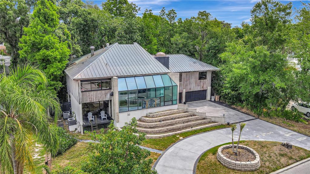 An aerial view shows a modern house with a large glass atrium and tiered landscaping — 312 S RIVERHILLS DRIVE, TAMPA, FL