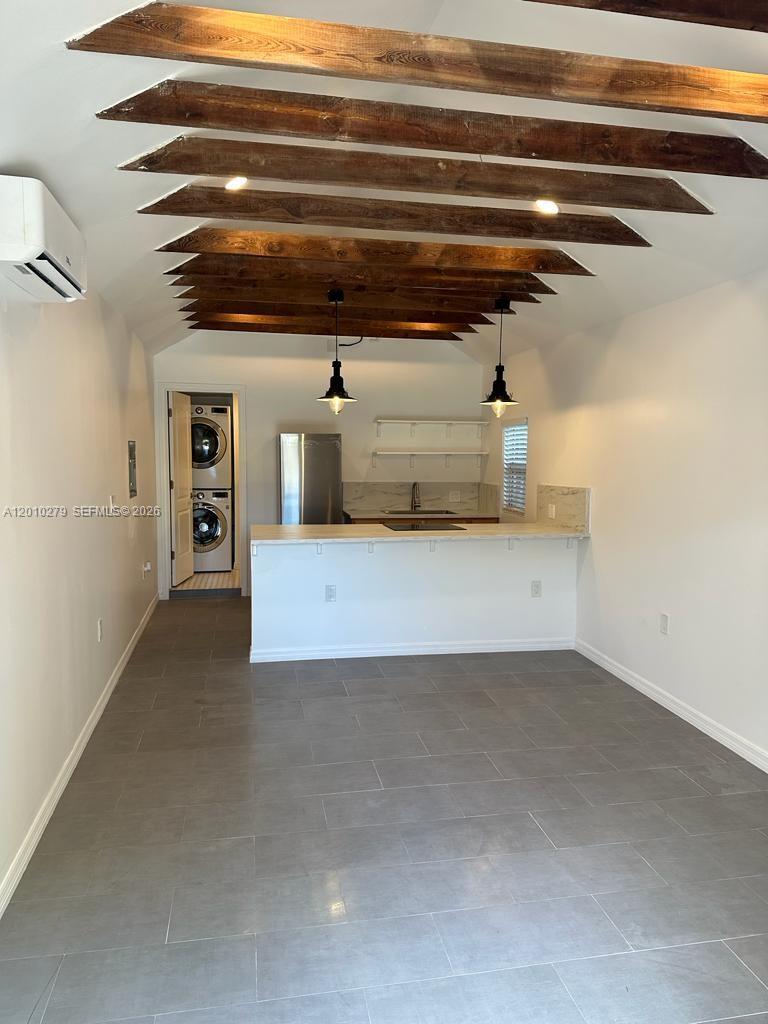 A kitchen and living area features exposed ceiling beams, gray tile flooring, and a laundry closet — 3113 SW 14th St # A, Miami FL 33145, MIAMI, FL