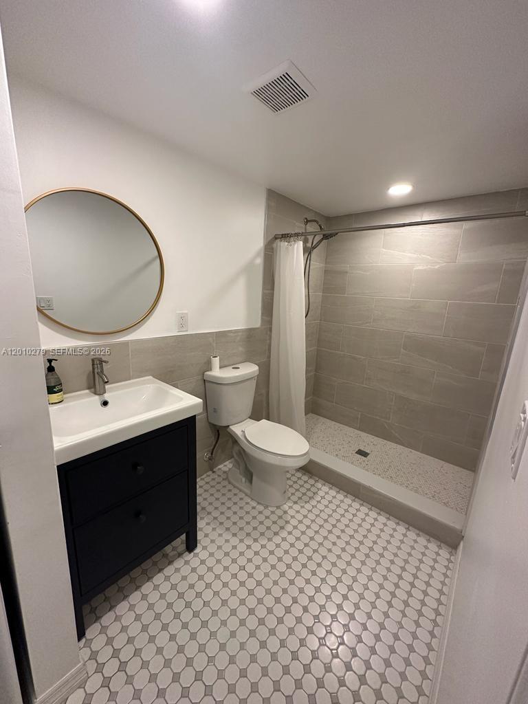 A bathroom features a dark vanity, a round mirror, a toilet, and a tiled shower — 3113 SW 14th St # A, Miami FL 33145, MIAMI, FL