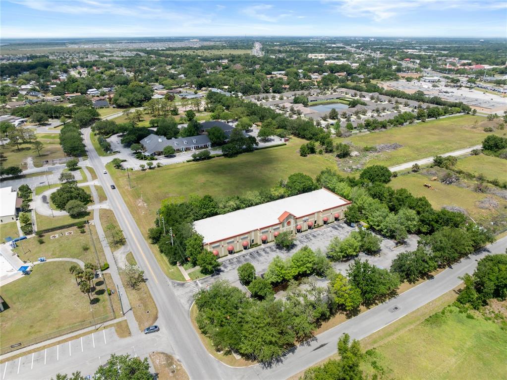 An aerial view shows a commercial building with a parking lot surrounded by green space — 3000 17TH STREET, ST CLOUD, FL