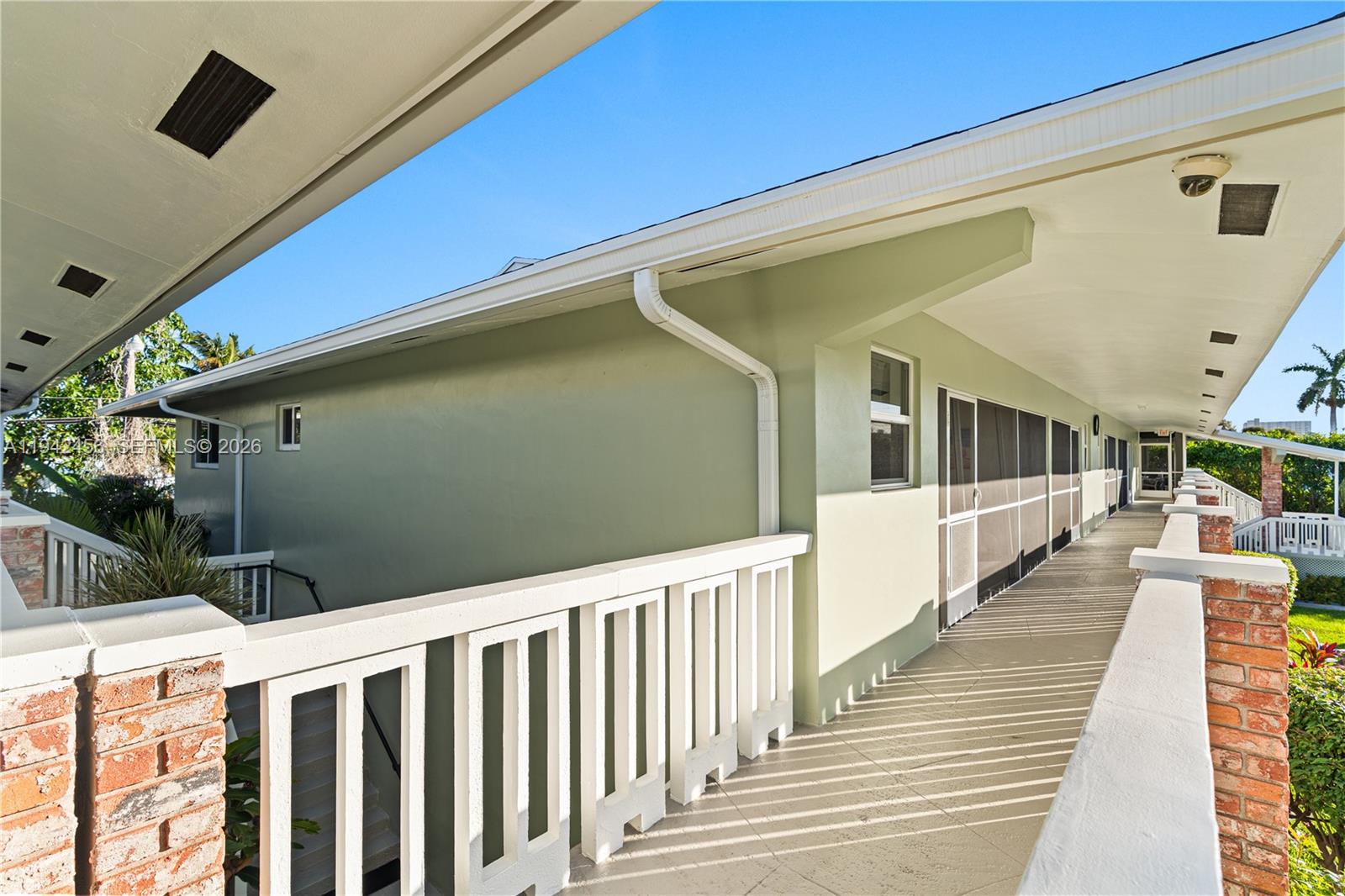 An outdoor walkway with white railings runs alongside a light green building exterior — 2541 NE 11th St # 212, Pompano Beach FL 33062, POMPANO BEACH, FL