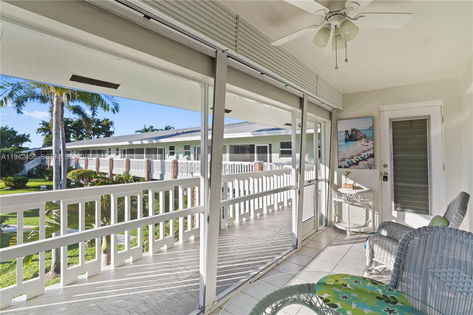 A screened-in balcony features tiled flooring, wicker furniture, a ceiling fan, and exterior views — 2541 NE 11th St # 212, Pompano Beach FL 33062, POMPANO BEACH, FL