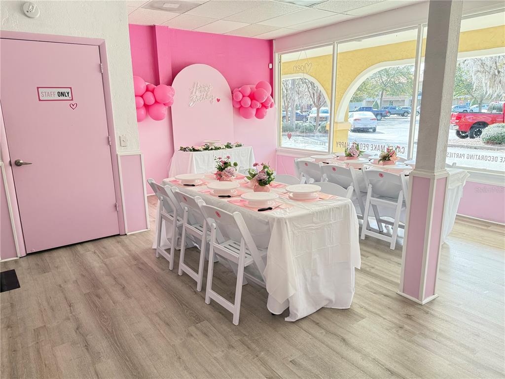 A bright pink party room features white tables, folding chairs, and large windows — 4127 NW 16TH BOULEVARD, GAINESVILLE, FL