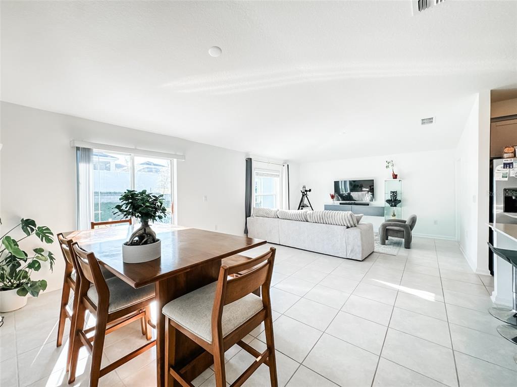 A dining area with a wooden table and chairs opens into a bright living room — 1828 PERCH HAMMOCK LOOP, GROVELAND, FL