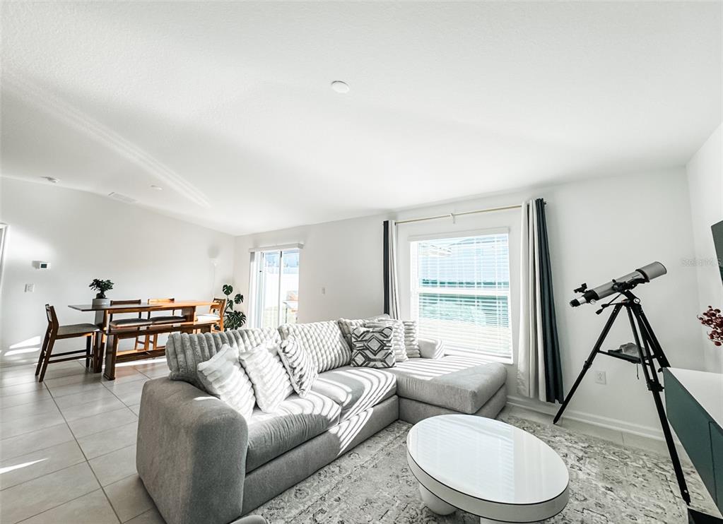 A bright living room features a gray sectional sofa, a white coffee table, and a telescope — 1828 PERCH HAMMOCK LOOP, GROVELAND, FL