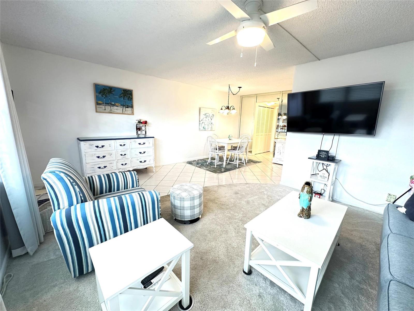 A living room with a striped armchair, white coffee table, and an adjacent dining area — 131 Oakridge J # 131, Deerfield Beach FL 33442, DEERFIELD BEACH, FL