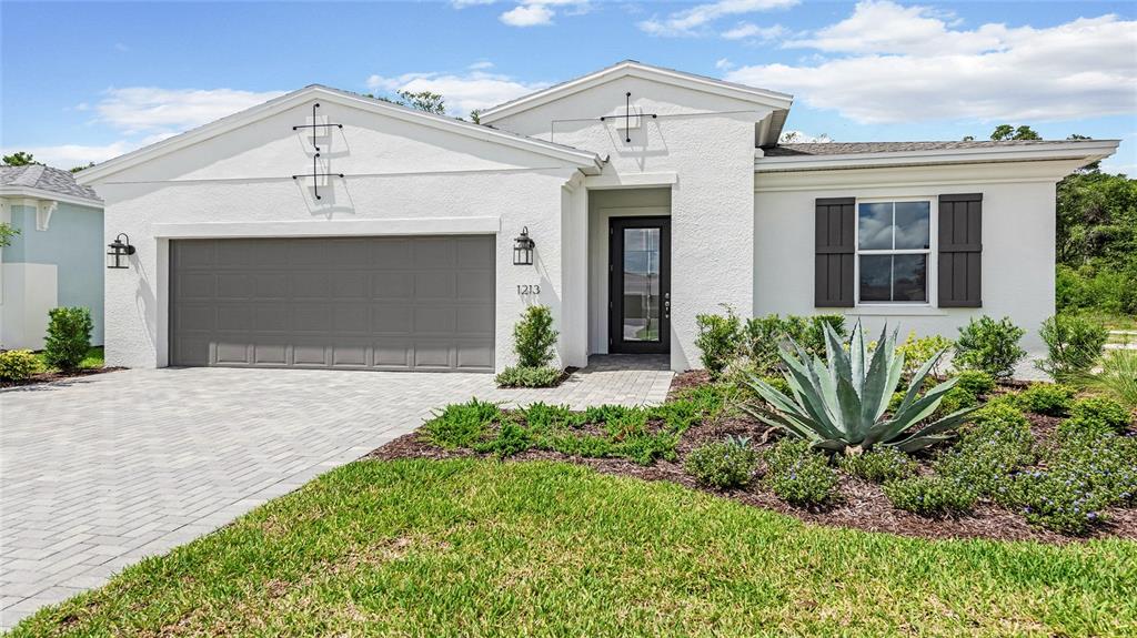 A white stucco house features a gray garage door, a front entrance, and landscaped yard — 1213 CRESSWIND BOULEVARD, DELAND, FL