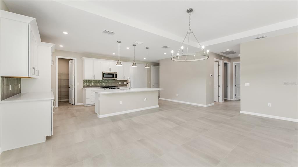 A modern kitchen features white cabinetry, a central island, and light-colored tile flooring — 1213 CRESSWIND BOULEVARD, DELAND, FL