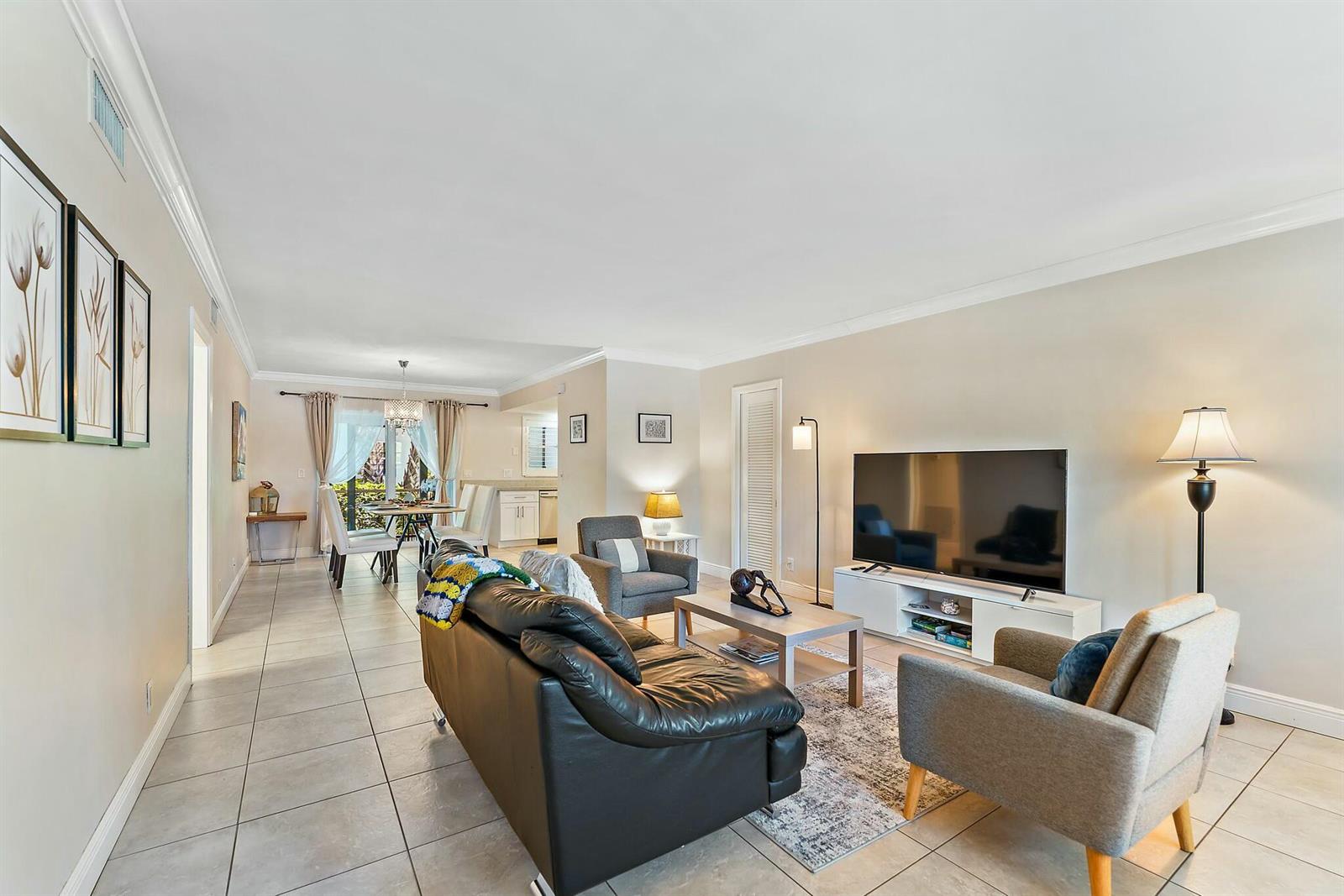 A living room with tile floors, a black leather sofa, and a television console — 3036 Park Avenue, Riviera Beach FL 33404, RIVIERA BEACH, FL