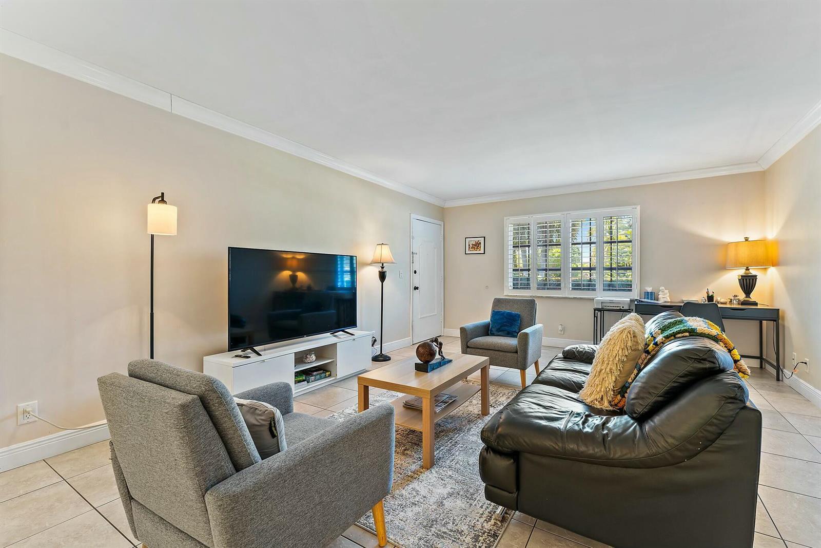 A living room features tile flooring, a black leather sofa, two gray armchairs, and furniture — 3036 Park Avenue, Riviera Beach FL 33404, RIVIERA BEACH, FL