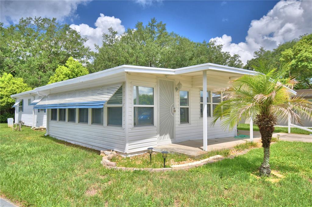 A white mobile home features a screened-in porch, a palm tree, and a grassy yard — 111 PARADISE LANE, AUBURNDALE, FL