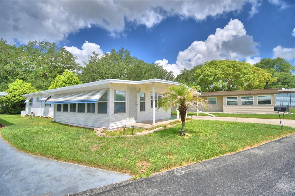 A white manufactured home with a covered porch and a small palm tree in front — 111 PARADISE LANE, AUBURNDALE, FL