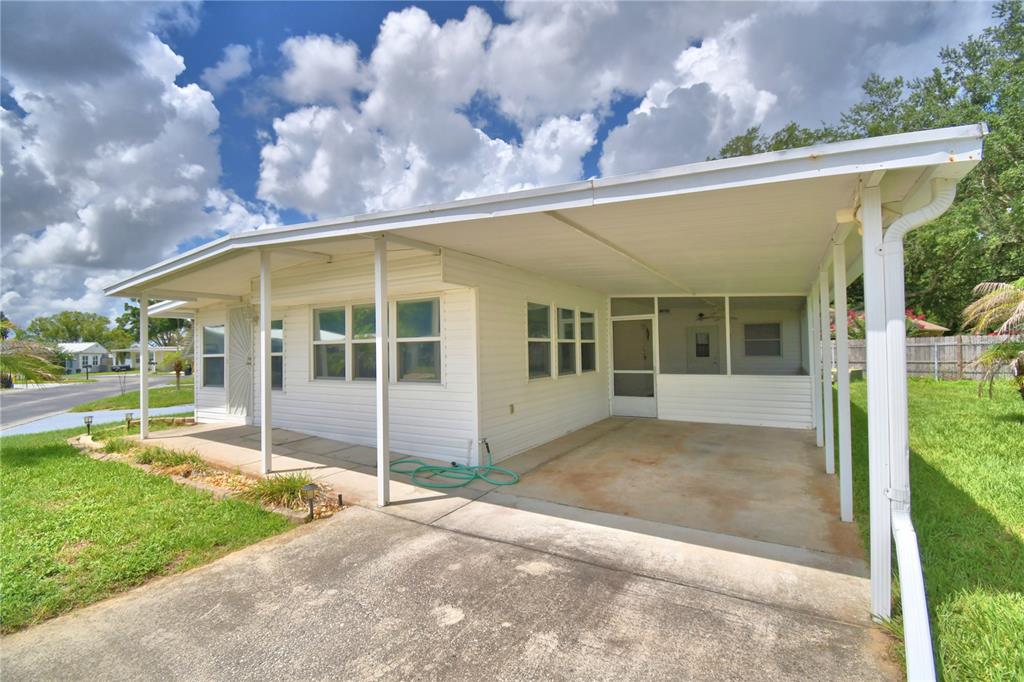 A white single-story house with a carport and a screened-in porch under a metal roof — 111 PARADISE LANE, AUBURNDALE, FL