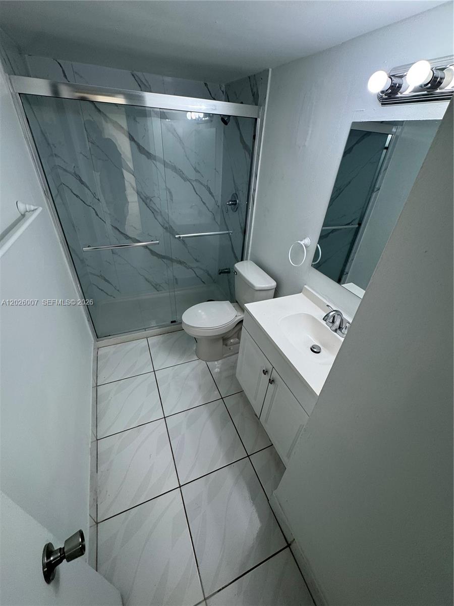 A bathroom features a glass-enclosed shower, a white vanity, and light-colored tile flooring — 1555 W 44th Pl # 244, Hialeah FL 33012, HIALEAH, FL