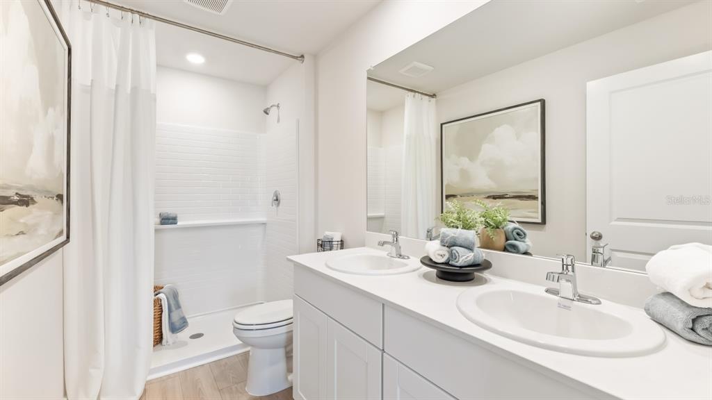 A bathroom features a double vanity, a white shower with subway tile, and light flooring — 1481 HARMON DRIVE, PORT CHARLOTTE, FL