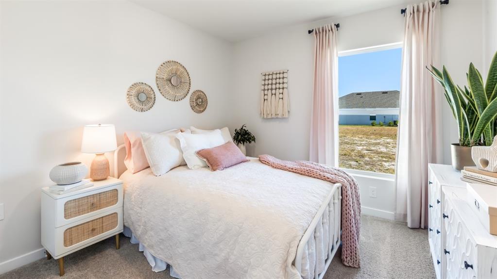 A bedroom features a white metal bed, a rattan nightstand, and a window with curtains — 1481 HARMON DRIVE, PORT CHARLOTTE, FL