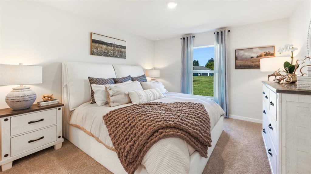 A bedroom features a white upholstered bed, a brown knit throw, and white wooden furniture — 1481 HARMON DRIVE, PORT CHARLOTTE, FL