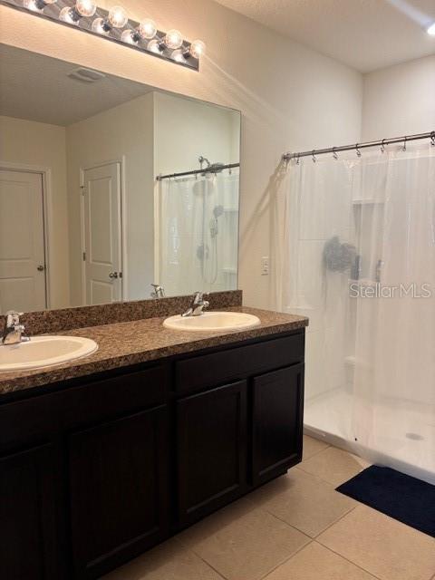 A bathroom features a double vanity with dark cabinets, granite countertops, and a walk-in shower — 32696 PEZ LANDING LANE, WESLEY CHAPEL, FL