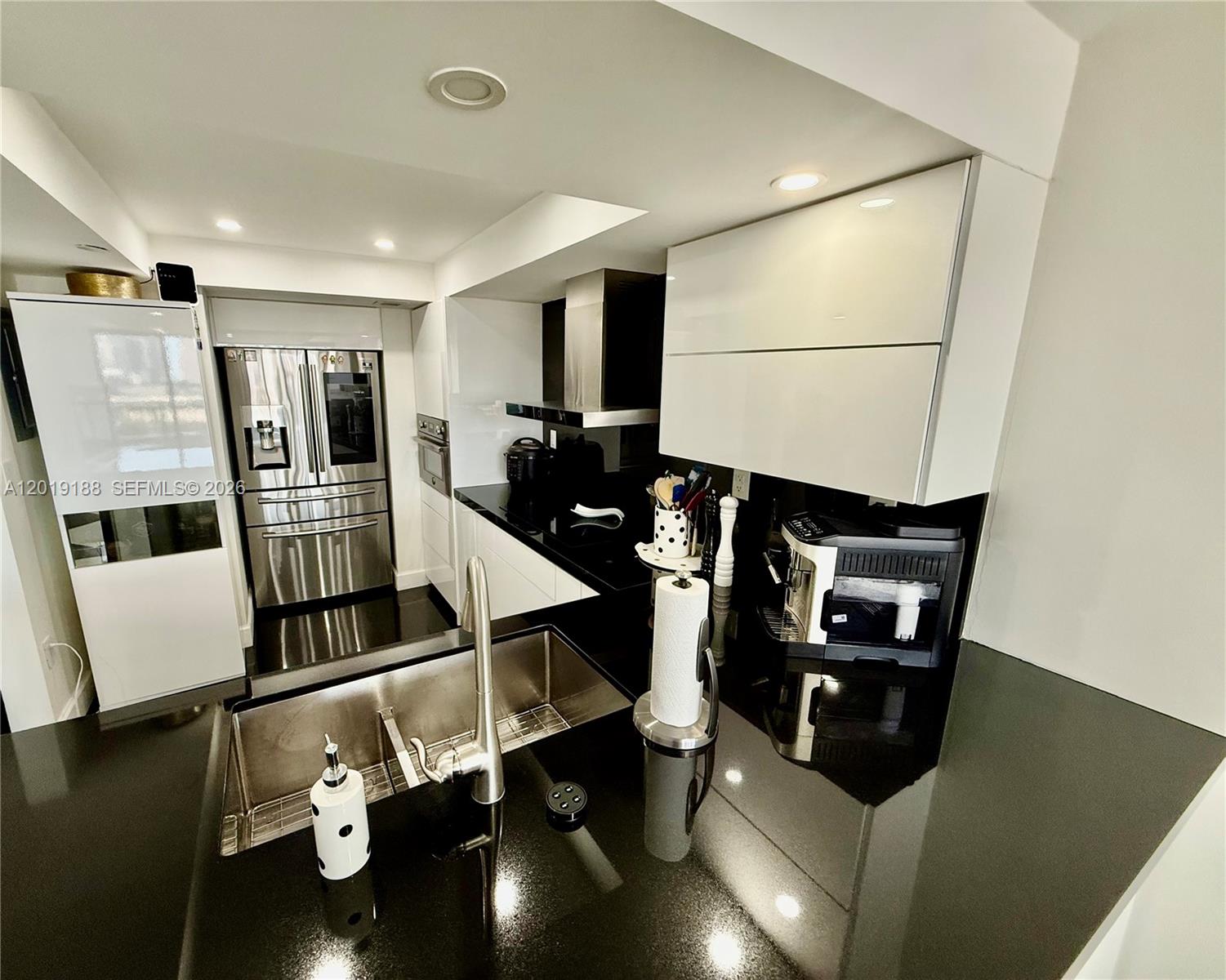 A modern kitchen features black countertops, white cabinetry, and stainless steel appliances — 555 NE 15th St # 15H, Miami FL 33132, MIAMI, FL