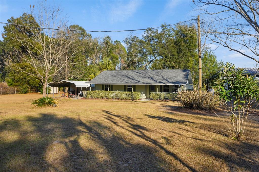 A single-story house with a gray roof and a carport sits on a grassy lot — 6878 SW 36TH AVENUE, LAKE BUTLER, FL