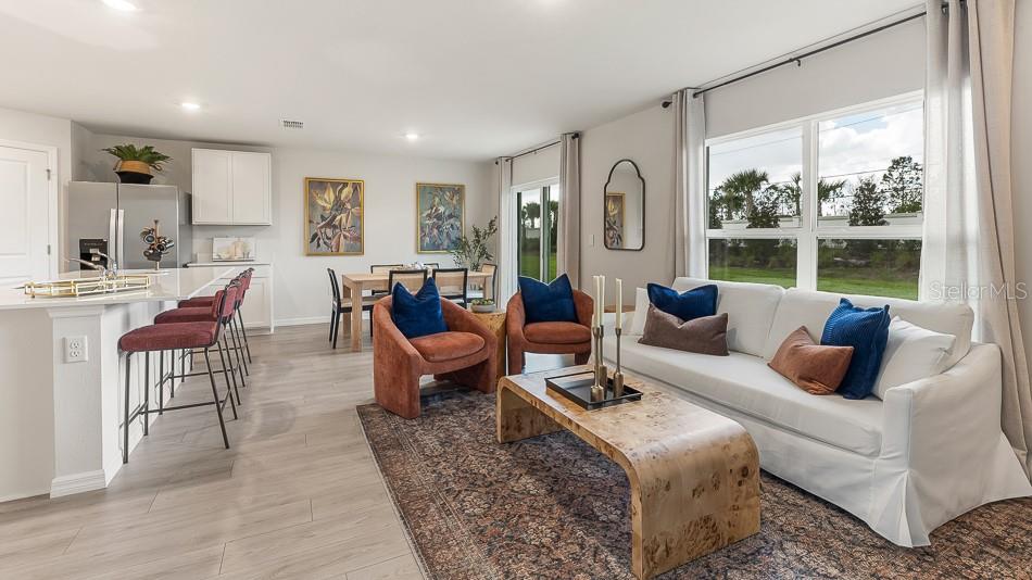 An open-concept living and dining area features a white sofa, two armchairs, and kitchen island — 12416 HOPSCOTCH AVENUE, PARRISH, FL
