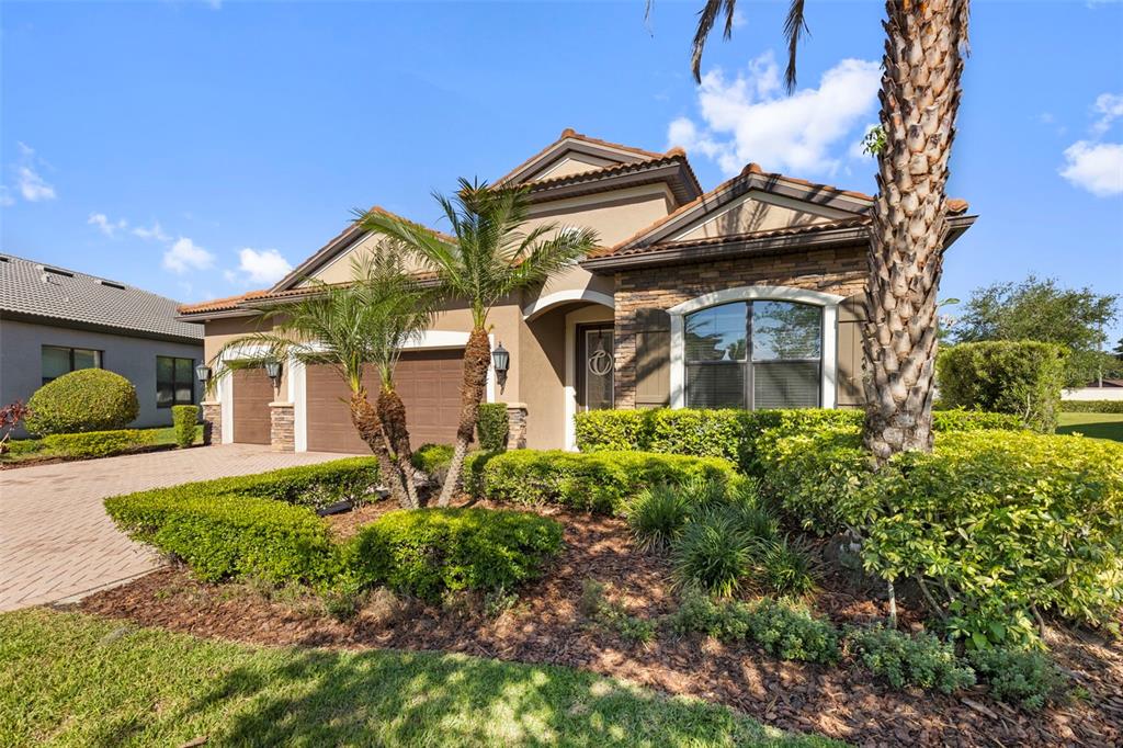 A single-story house with a stone facade, brown garage doors, and landscaped front yard — 5134 LAKECASTLE DRIVE, TAMPA, FL