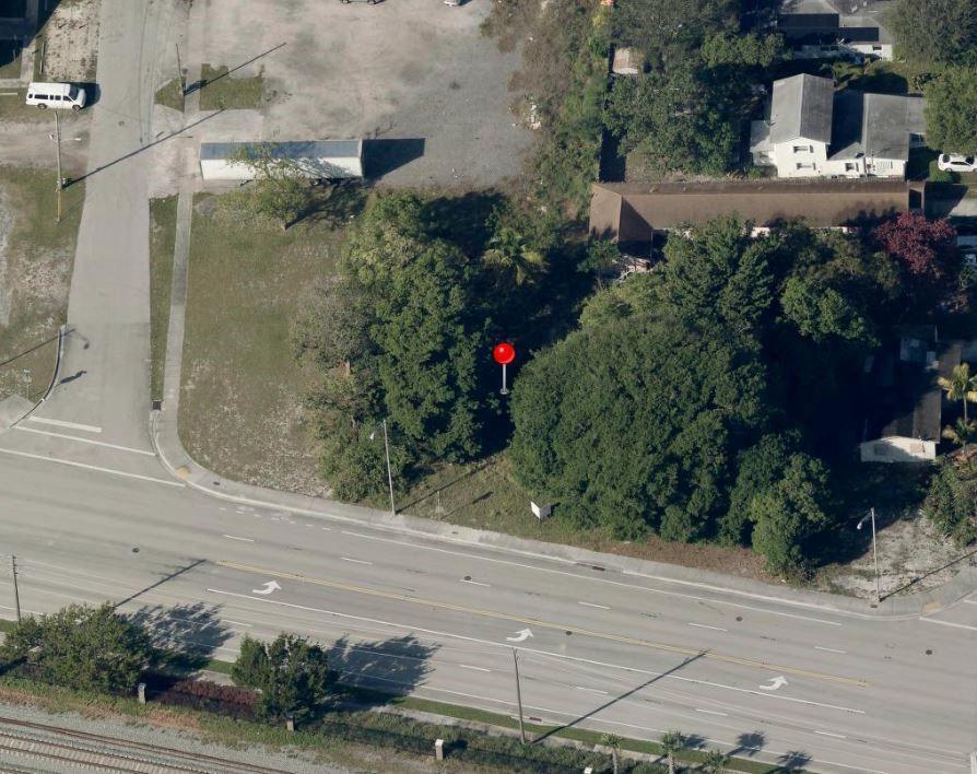 An aerial view shows a vacant, tree-covered lot situated next to a road and buildings — 583 S Dixie Highway, Deerfield Beach FL 33441, DEERFIELD BEACH, FL