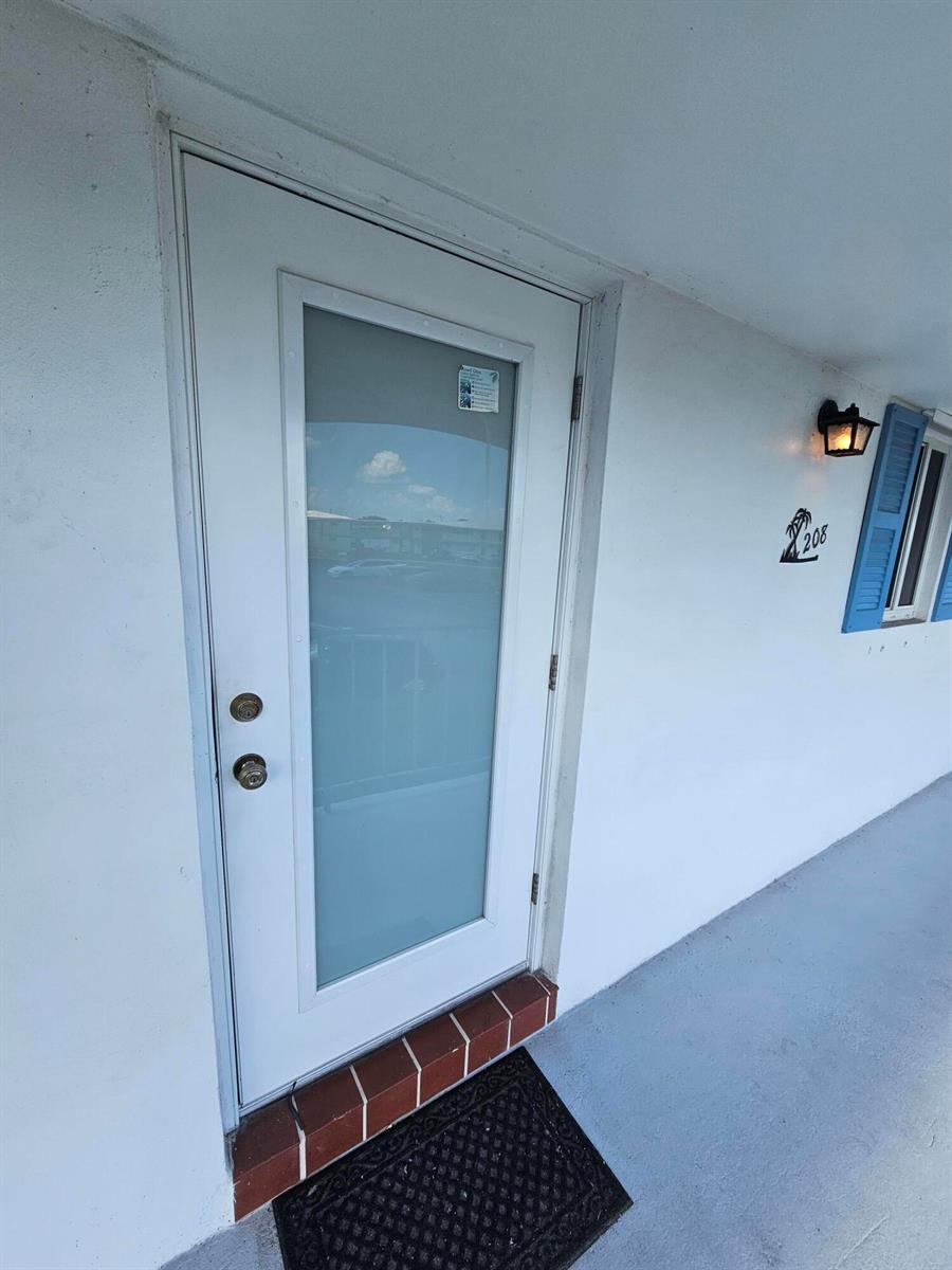 A white exterior door with a frosted glass panel is mounted on a building wall — 1115 Lake Terrace # 208, Boynton Beach FL 33426, BOYNTON BEACH, FL