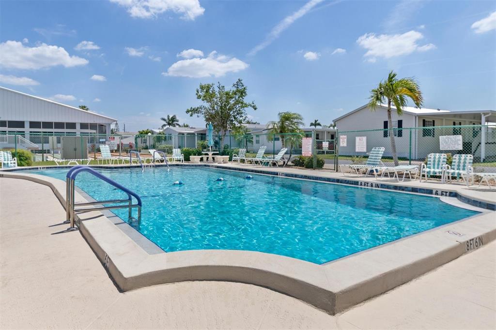 An outdoor swimming pool with a concrete deck and lounge chairs under a blue sky — 4300 RIVERSIDE DRIVE UNIT 14, PUNTA GORDA, FL