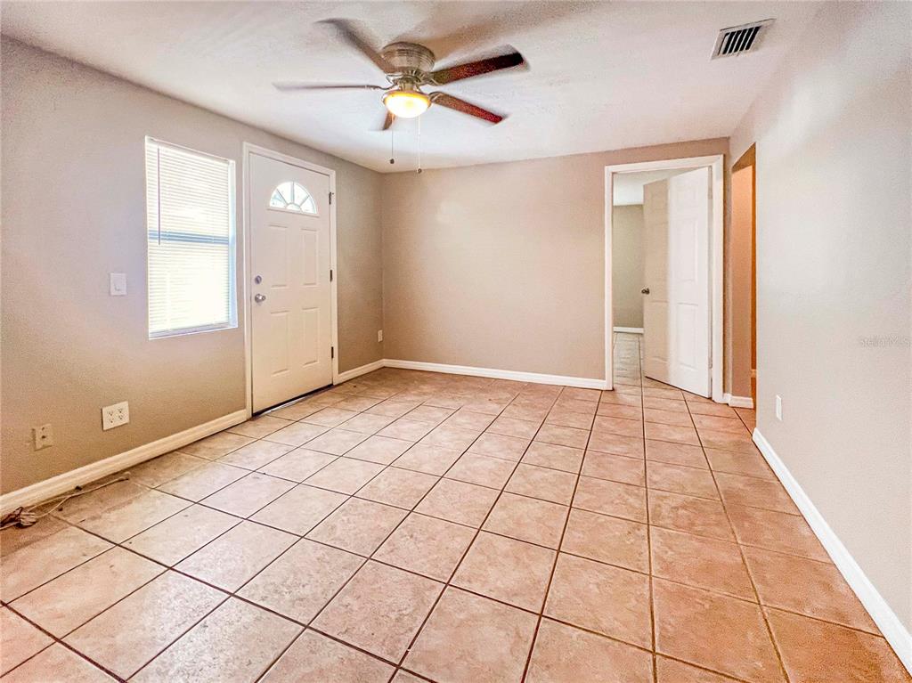 An empty room with tan walls, tiled flooring, a ceiling fan, and a white door — 2137 ROSELAWN STREET UNIT A, SARASOTA, FL