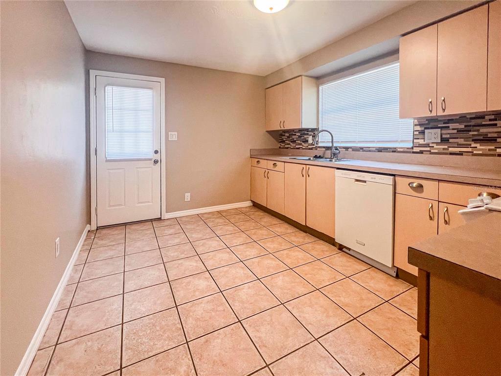 A kitchen with light wood cabinets, a dishwasher, tile flooring, and a glass-paneled exterior door — 2137 ROSELAWN STREET UNIT A, SARASOTA, FL