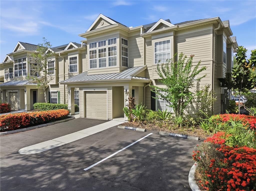A tan two-story townhouse with a single-car garage and a paved parking area — 7780 PLANTATION CIRCLE, BRADENTON, FL