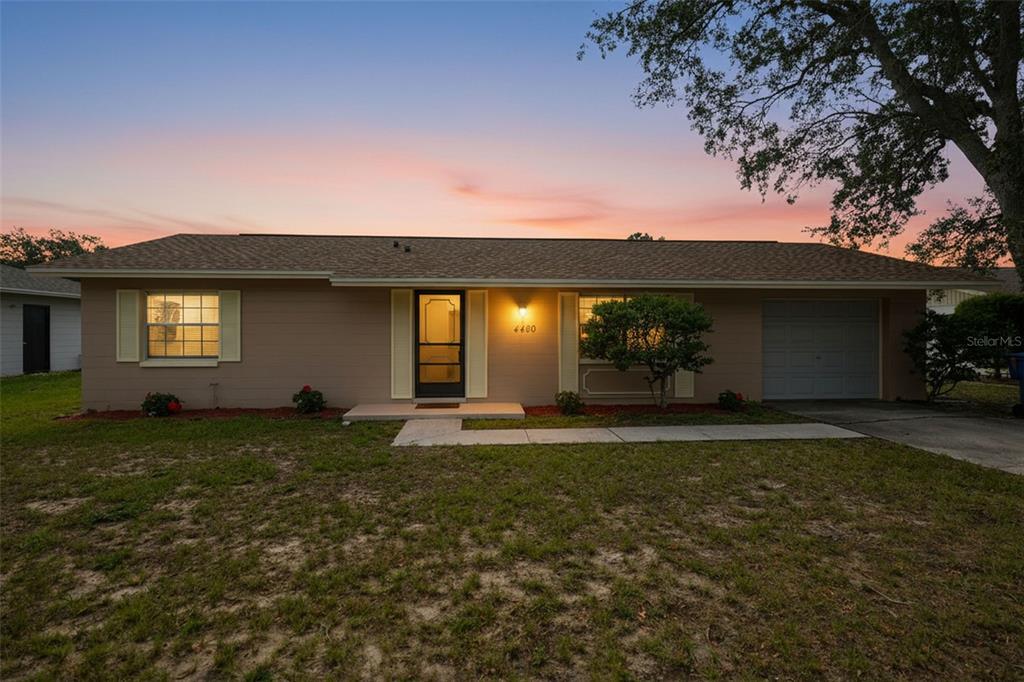 A single-story house with a tan exterior, a front door, and an attached garage — 4480 BROMLEY AVENUE, SPRING HILL, FL