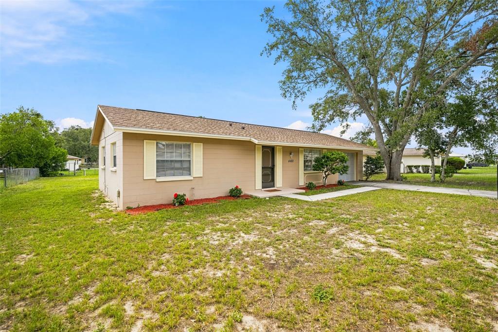 A single-story tan house with a brown shingled roof sits on a grassy lot — 4480 BROMLEY AVENUE, SPRING HILL, FL