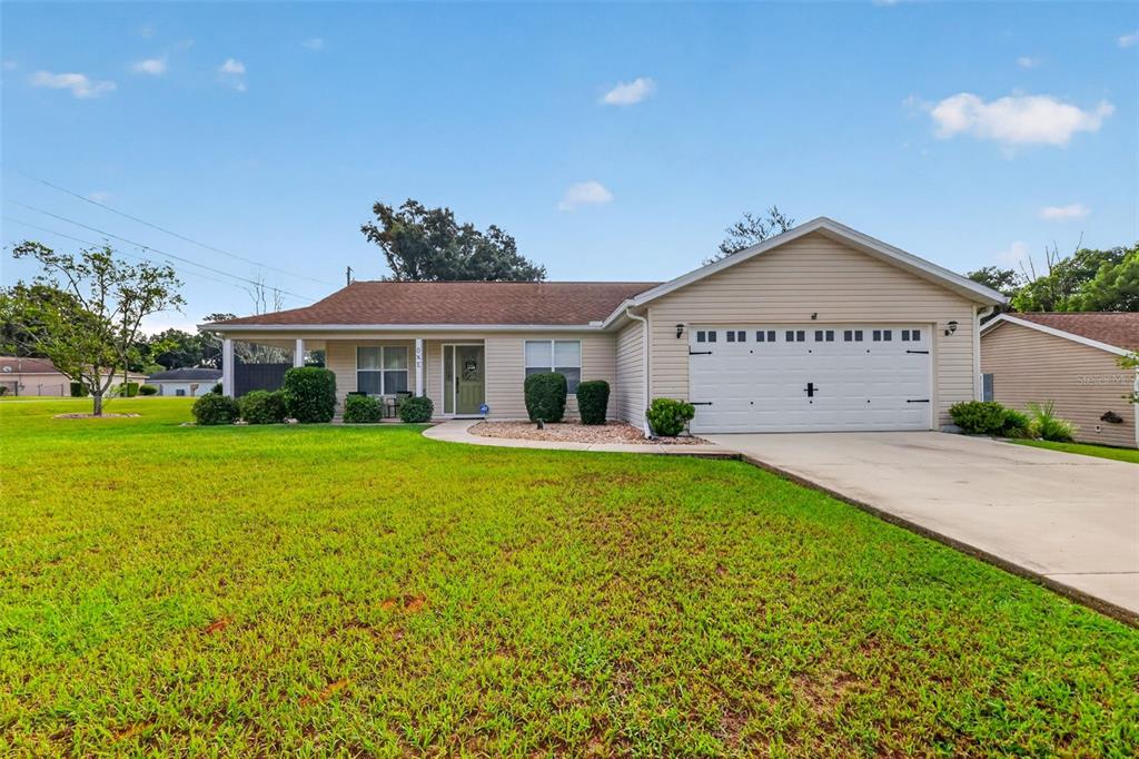 A single-story house with beige siding, a two-car garage, and a large front lawn — 1 TEAK COURT, OCALA, FL
