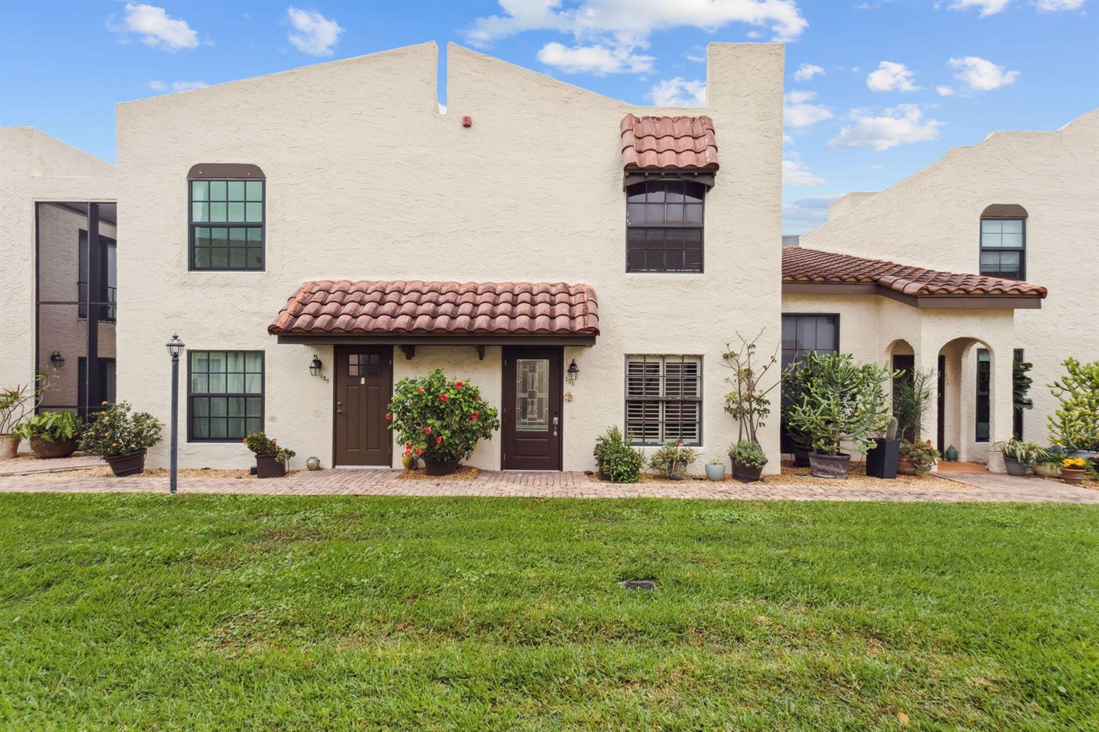 A two-story stucco townhouse exterior features a tiled roof, brown doors, and a front lawn — 200 S Ocean Boulevard # 135, Delray Beach FL 33483, DELRAY BEACH, FL