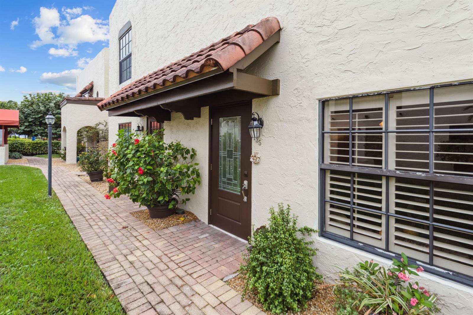 A brown front door sits under a tiled awning on a stucco building exterior — 200 S Ocean Boulevard # 135, Delray Beach FL 33483, DELRAY BEACH, FL