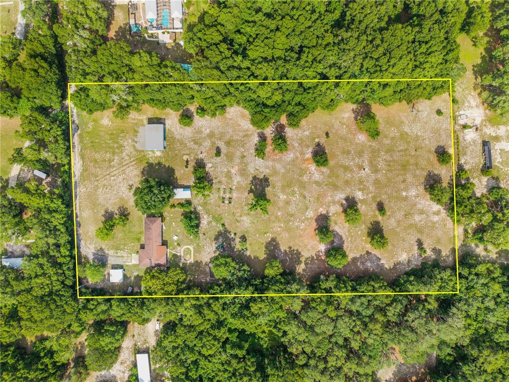 An aerial view shows a rectangular property with a house, outbuildings, and scattered trees — 1167 OHIO STREET, DE LEON SPRINGS, FL