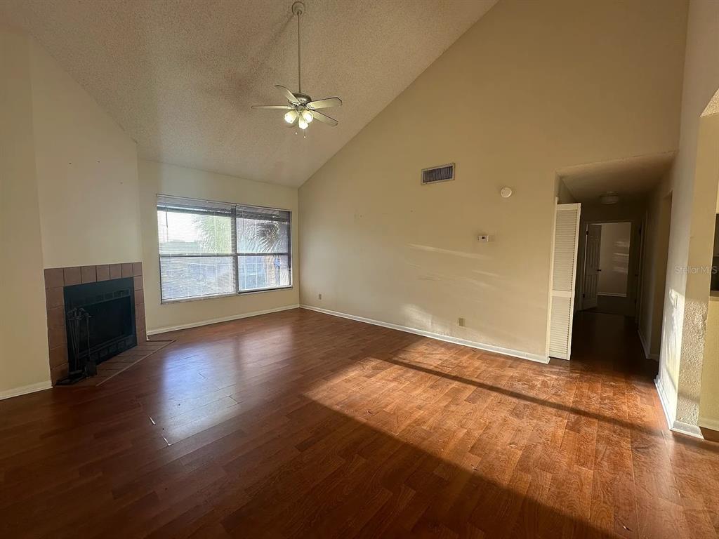 A living room with wood flooring, a vaulted ceiling, a ceiling fan, and a fireplace — 2050 SAN MARCOS DRIVE SE UNIT 214, WINTER HAVEN, FL