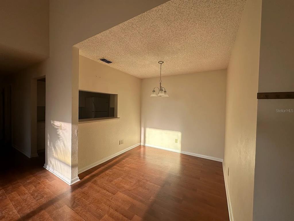 A dining area features wood-look flooring, a textured ceiling, and a hanging light fixture — 2050 SAN MARCOS DRIVE SE UNIT 214, WINTER HAVEN, FL