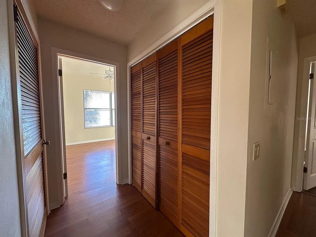 A hallway features wood-toned louvered closet doors and a doorway leading to a bedroom — 2050 SAN MARCOS DRIVE SE UNIT 214, WINTER HAVEN, FL