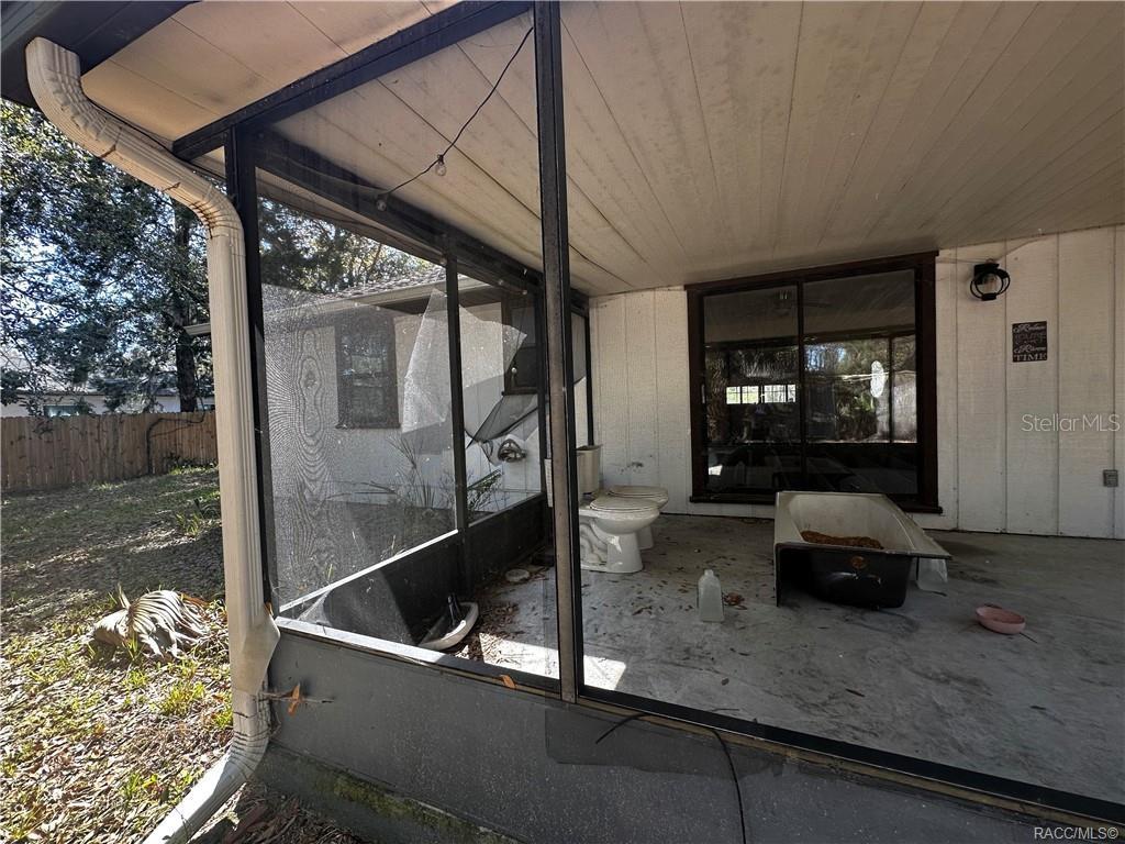 A screened-in porch contains a toilet and a bathtub sitting on a concrete floor — 4197 N CONCORD DRIVE, CRYSTAL RIVER, FL