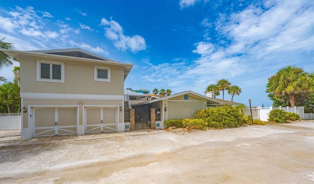 A two-story house with a two-car garage and a paved driveway under a blue sky — 2308 BEACH TRAIL, INDIAN ROCKS BEACH, FL